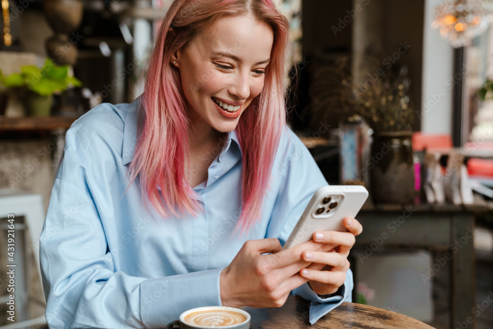 Young smiling woman using mobile phone while sitting in cafe Young smiling woman using mobile phone while sitting in cafe