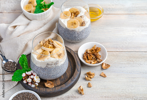 Chia pudding with banana, nuts and honey on a beige background with space to copy. A healthy, vitamin-rich breakfast. The concept of diet and healthy eating.