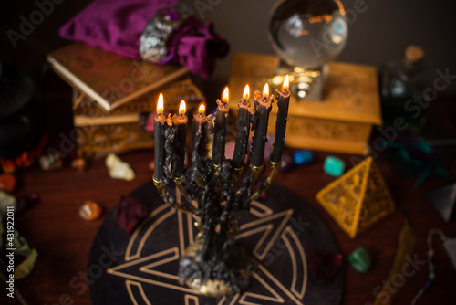 A fortune teller, witch stuff on a table, candles and fortune-telling objects. The concept of divination, astrology and esotericism