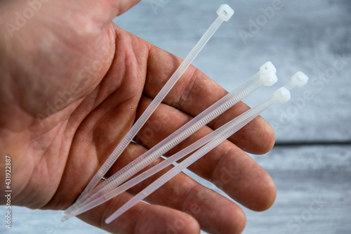 Plastic white ties in the hand on a gray background.