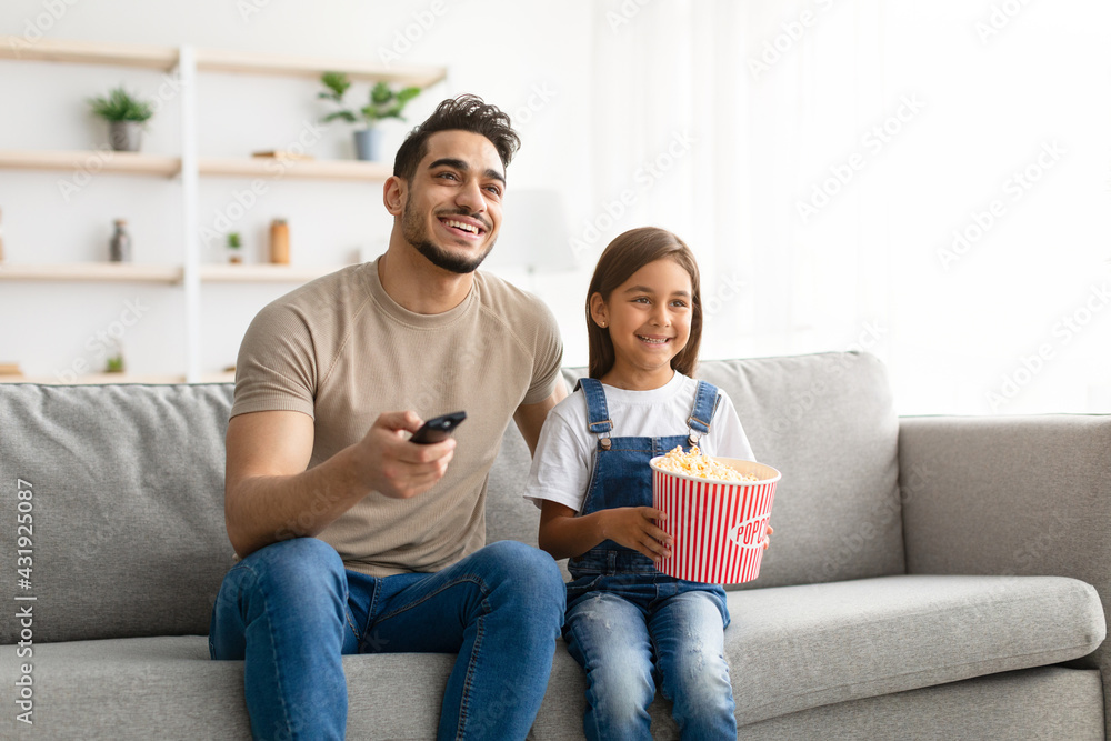 Happy young family watching television sitting on couch Happy young family watching television sitting on couch