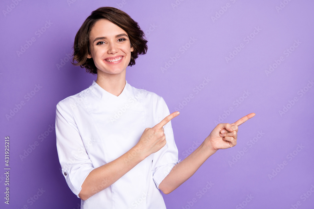 Photo of cheerful nice young woman point fingers empty space chef information isolated on violet color background Photo of cheerful nice young woman point fingers empty space chef information isolated on violet color background