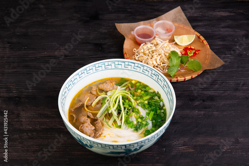 soup with pieces of veal, rice noodles, green onions, lime, pepper photo