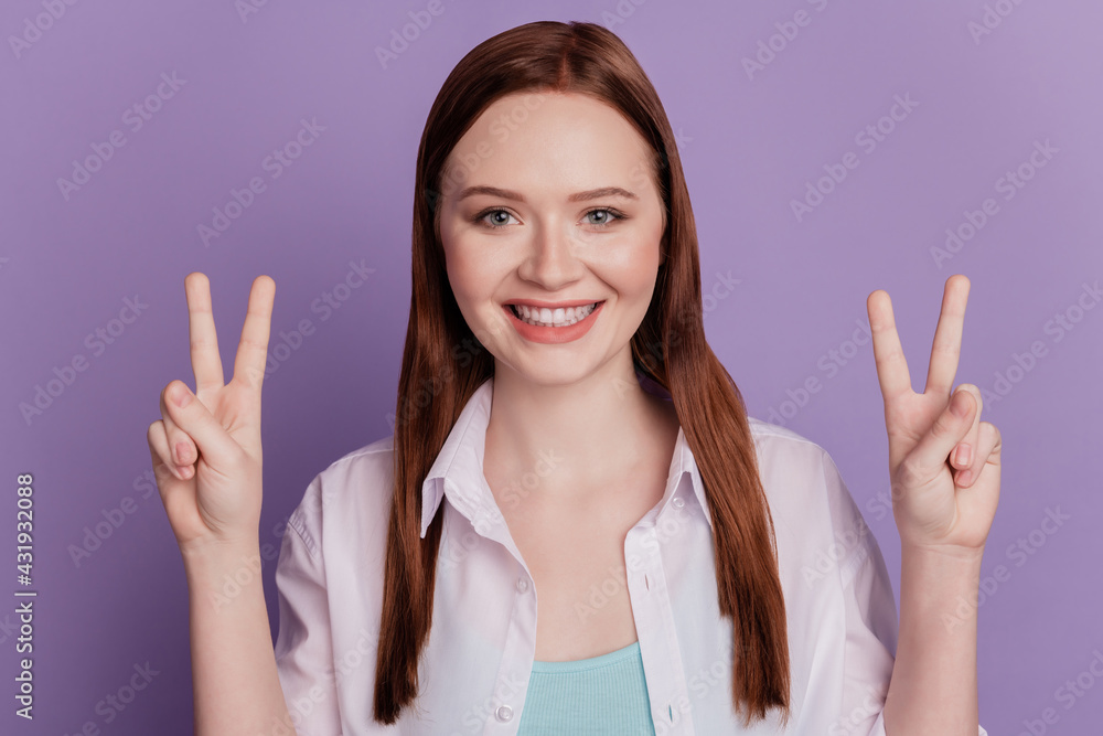 Portrait of cheerful lady hands show two v-signs look camera on purple wall Portrait of cheerful lady hands show two v-signs look camera on purple wall