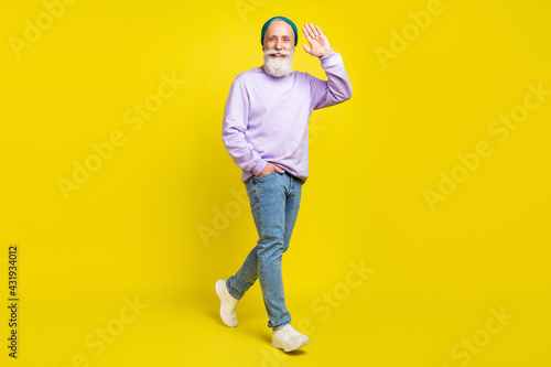 Full length body size photo of smiling elder man going forward waving hand greeting isolated on bright yellow color background