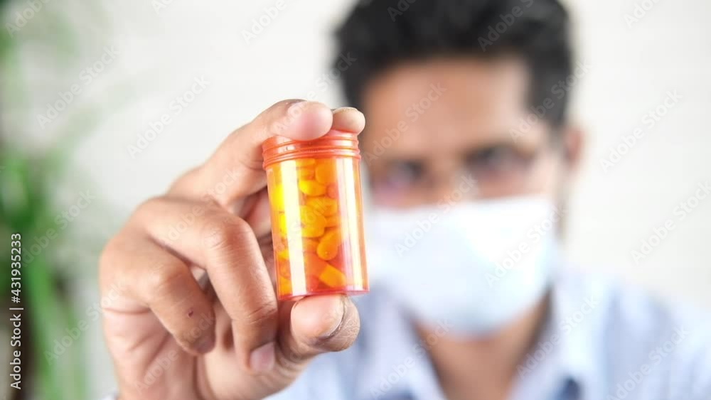 man in surgical face mask hand holding pill container man in surgical face mask hand holding pill container