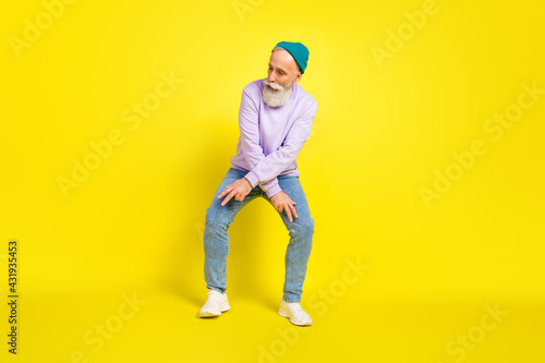 Photo of handsome attractive mature man dressed purple pullover headwear dancing smiling isolated yellow color background
