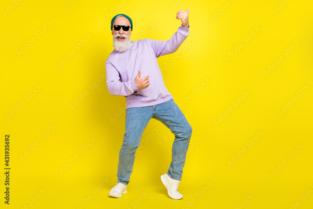 Photo of pretty cute mature man dressed purple pullover headwear spectacles dancing playing guitar isolated yellow color background Photo of pretty cute mature man dressed purple pullover headwear spectacles dancing playing guitar isolated yellow color background