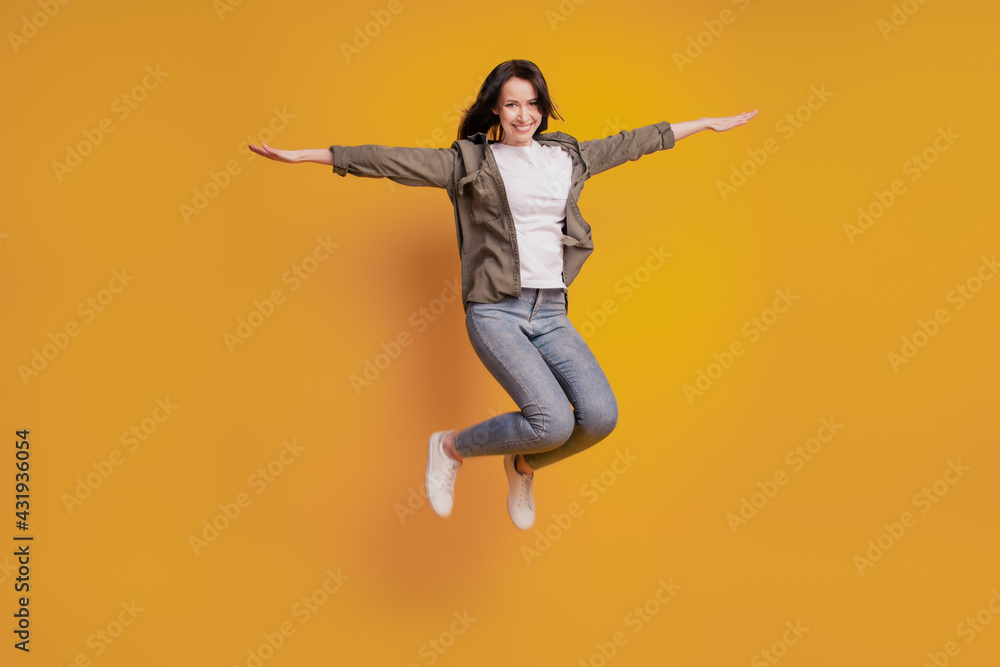 Full length photo of woman raise hands jump isolated over yellow background Full length photo of woman raise hands jump isolated over yellow background