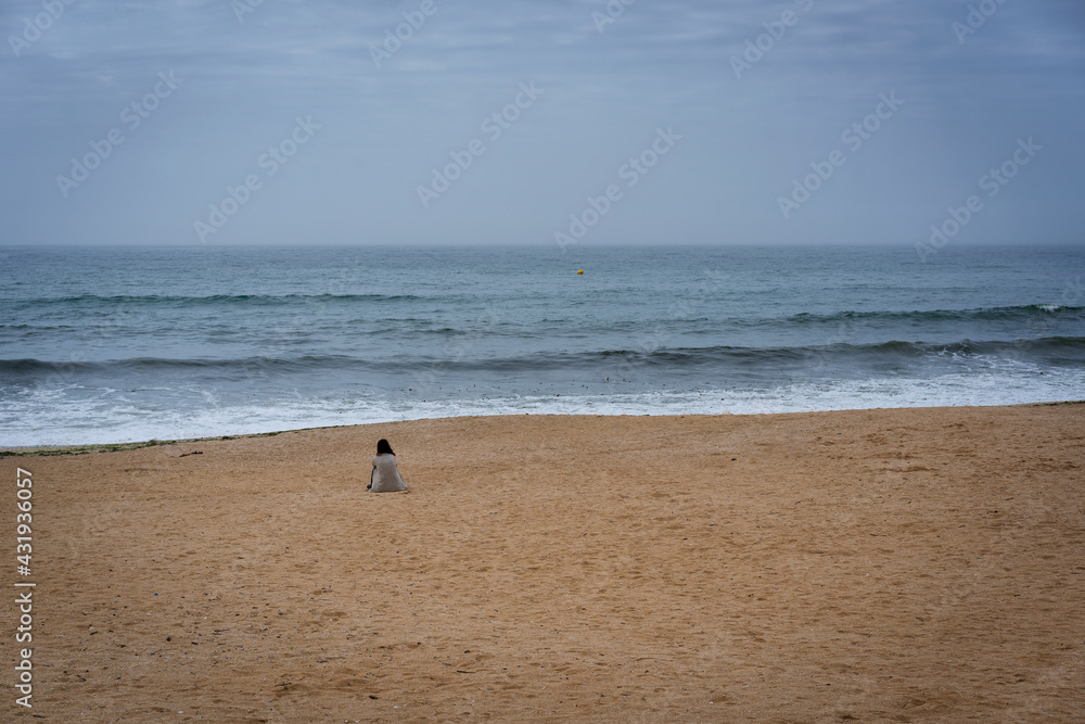 Caucasian woman sit and relaxing in the sand of Lanzada beach in Galicia