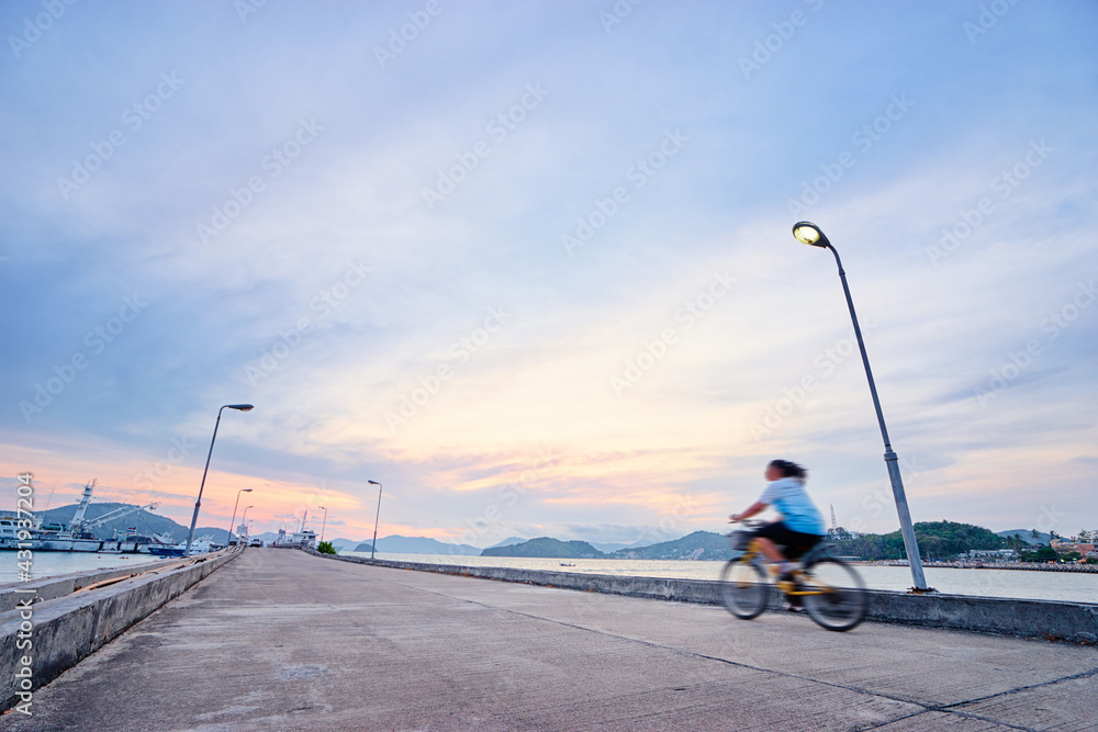 Sports lifestyle. Woman riding bicycle on the sea pier. Motion blur. Sports lifestyle. Woman riding bicycle on the sea pier. Motion blur.
