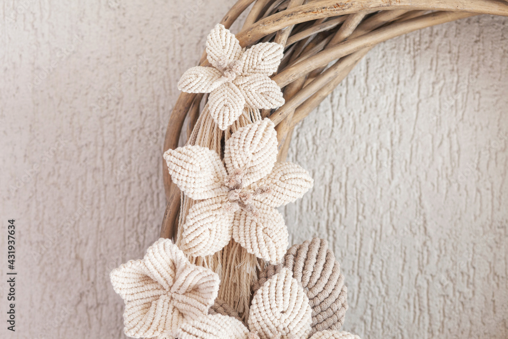 Macrame wreath with big cotton flower on a white decorative plaster wall. Natural cotton thread and rope. Eco decor for home. Creative greeting card for a creative person. Close up Macrame wreath with big cotton flower on a white decorative plaster wall. Natural cotton thread and rope. Eco decor for home. Creative greeting card for a creative person. Close up