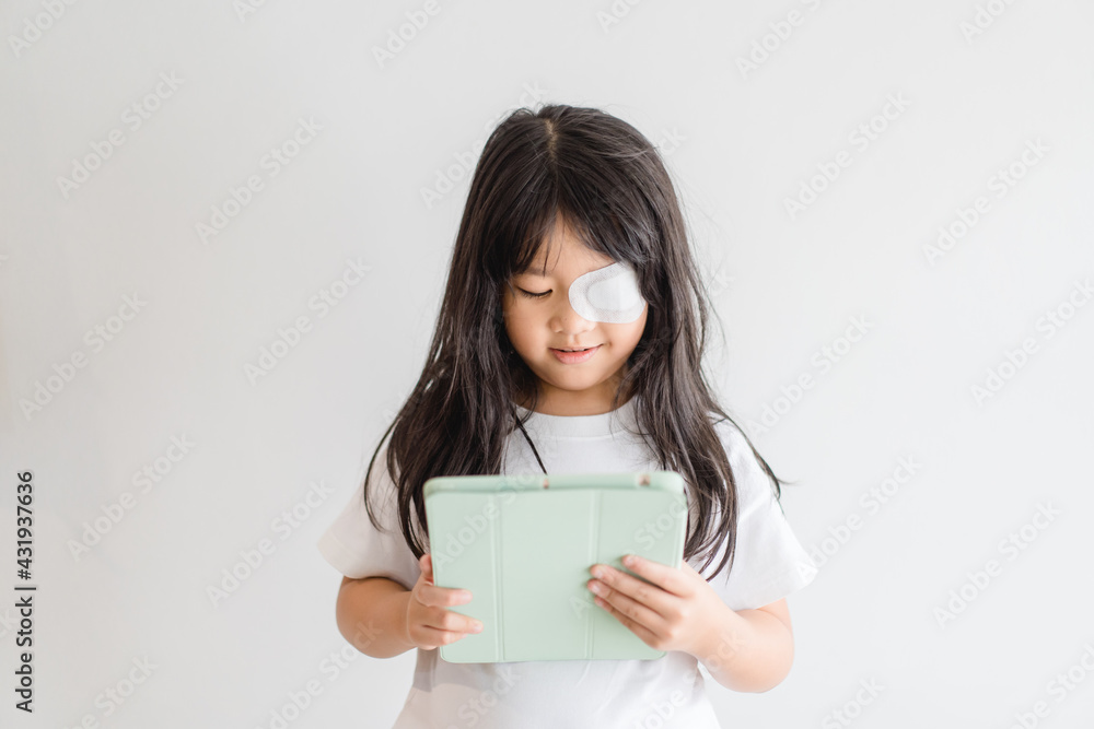 Lazy Eye amblyopia in children.Eye care.Little asian girl covered up with a special patch online learning at home.Occlusion therapy using an eye patch.Children care.child online learning education. Lazy Eye amblyopia in children.Eye care.Little asian girl covered up with a special patch online learning at home.Occlusion therapy using an eye patch.Children care.child online learning education.