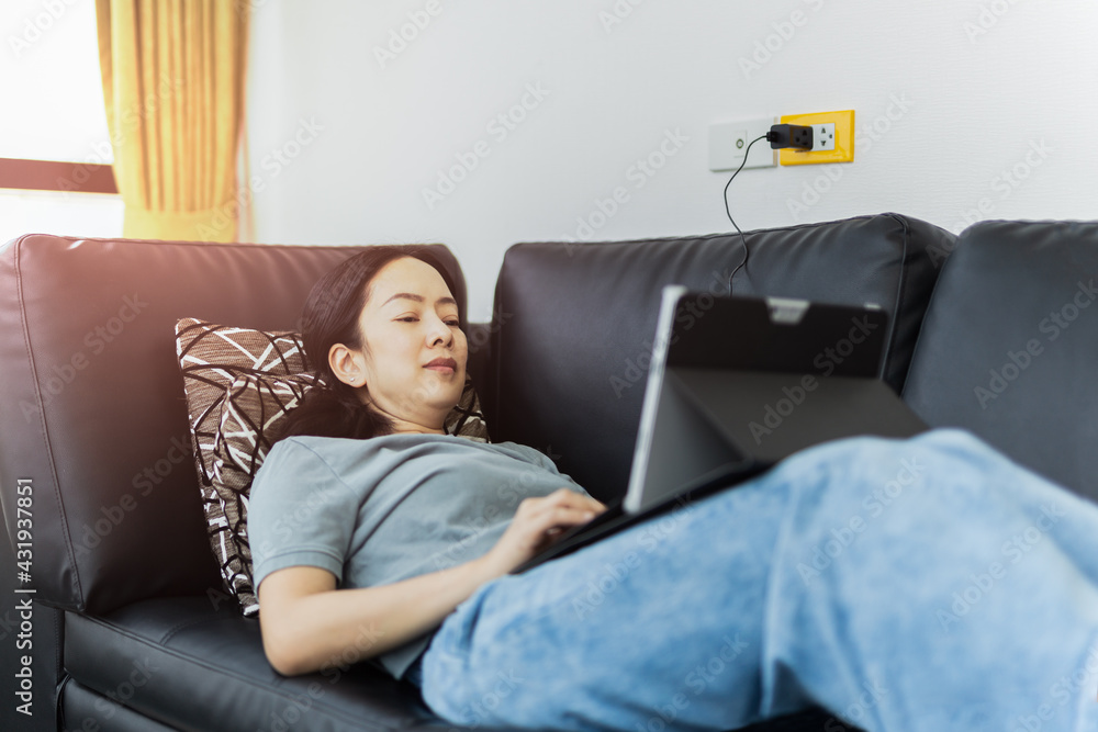 Caucasian woman lying on couch work on laptop.