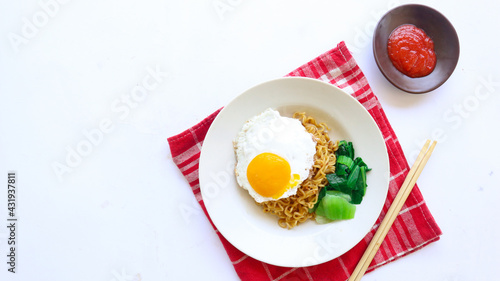 instant noodles served with egg fried and mustard greens on plate. instant fried noodle indomie 