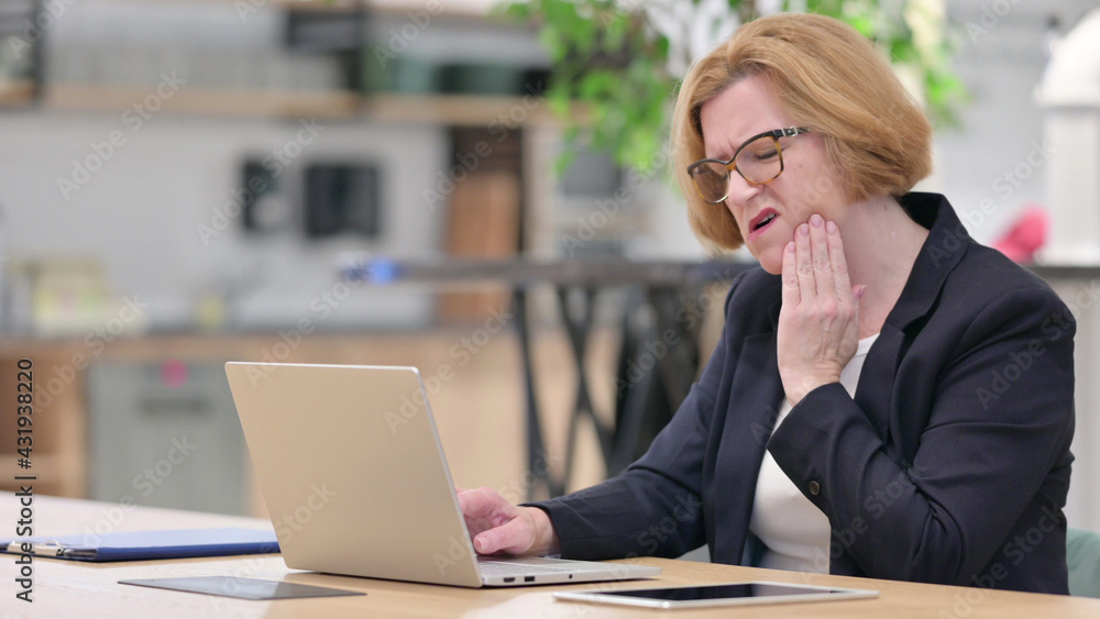 Old Businesswoman with Laptop having Toothache in Office Old Businesswoman with Laptop having Toothache in Office