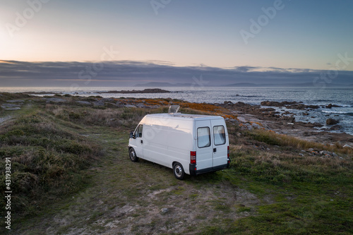 Camper van motorhome with solar panels drone aerial view on a sea landscape with mountains living van life in Galiza, Spain