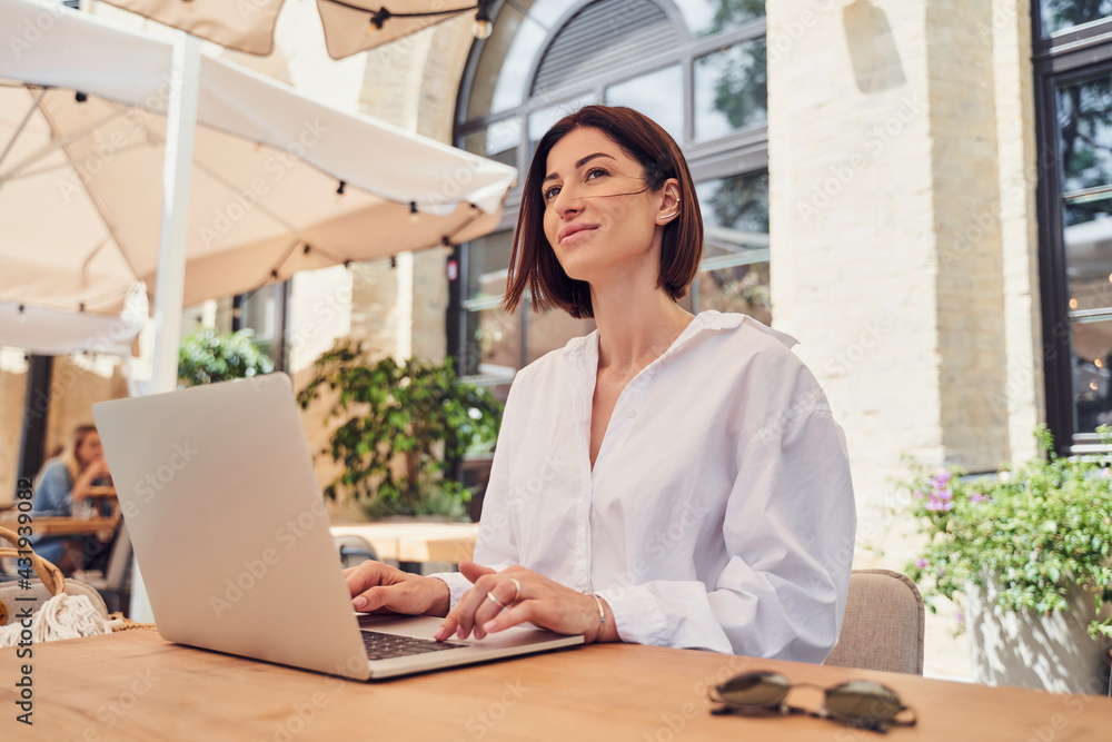Pritty business woman working on laptop in restaurant - obrazy, fototapety, plakaty 