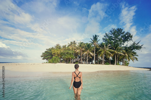 Vacation on the seashore. Back view of young woman swimming on the beautiful white sand beach tropical island.