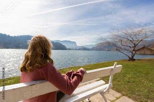 Young woman sitting on a bench by the shore of Lake Bled.