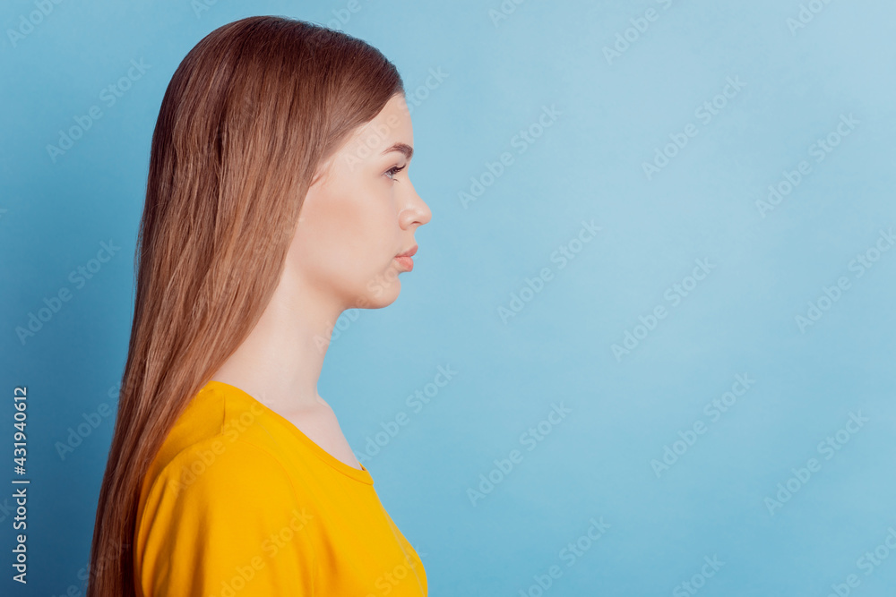 Profile portrait of calm girl look empty space on blue background Profile portrait of calm girl look empty space on blue background