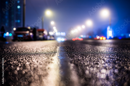 Foggy night in the big city   the headlights of the approaching cars on the road. Close up view from the level of the dividing line