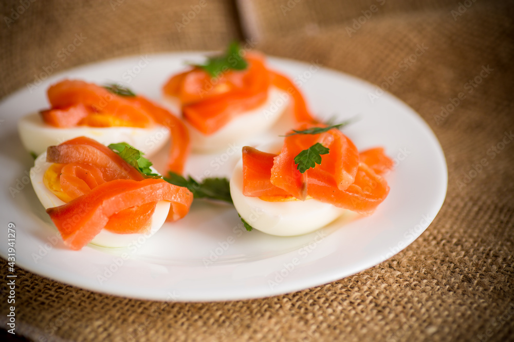 halves of boiled eggs with pieces of salted salmon