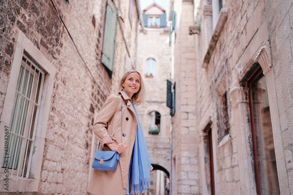 Traveling by croatia. happy young woman in coat walking by Split Old Town.