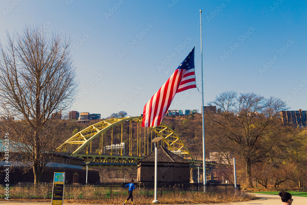 A nice weather means great time to explore the Point State Park in Pittsburgh Pennsylvania. On this picture, an American flag is visible as well as the Fort Pitt bridge and Fort Pitt Tunnel