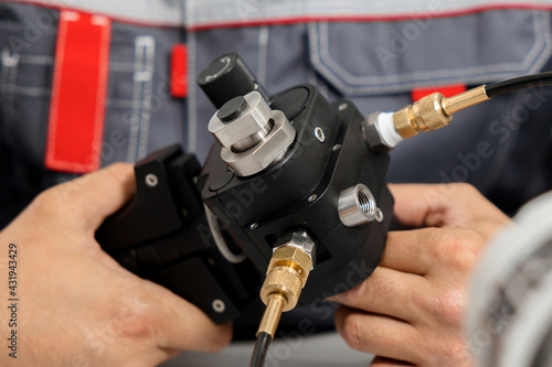 The metrology and standardization laboratory specialist connects the device under test pressure gauge to the pressure calibration and verification instrument. Checking international quality standards