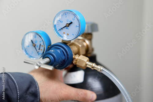 A metrology laboratory specialist takes a compressed gas cylinder for testing and calibration with a chromatograph. A man connects a hose for gas analysis. Gas analyzer and chromatography.