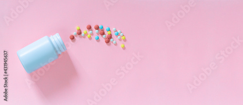 Pills and medicine bottles on a pink background,Multicolored tablets, pills, capsules in plastic bottle on pink background
