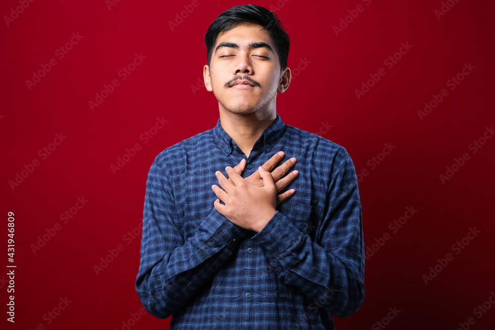 Fototapeta premium Handsome young man wearing casual clothes smiling with hands on chest with closed eyes and grateful gesture on face