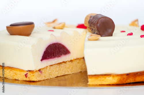 Section of vortex white glazed cake with a candies and chocolate sweets on brown dough. Side image.