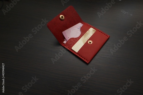 Leather red purse with money and a bank card. Wallet on a dark background
