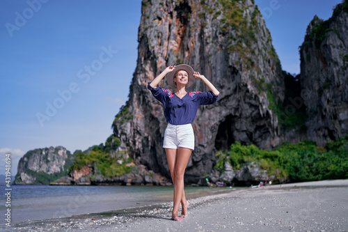 Tropical vacation. Happy young woman with hat walking on beach enjoying beautiful view in Thailand. © luengo_ua