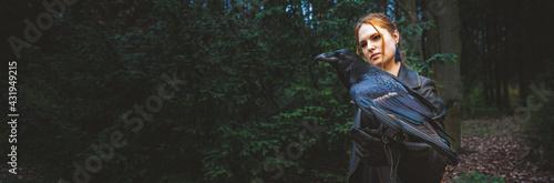 young woman or girl in the forest with a big black raven on his hand