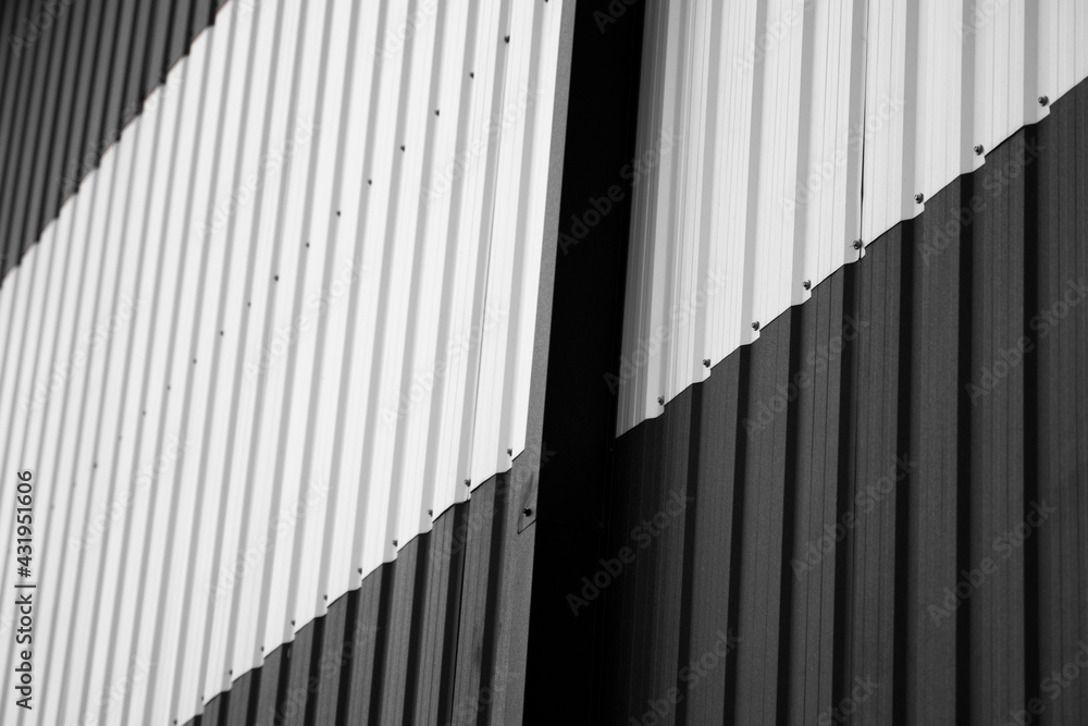 Black and white corrugated iron sheet used as a facade of a warehouse or factory. Texture of a seamless corrugated zinc sheet metal aluminum facade. Architecture. Metal texture. Black and white corrugated iron sheet used as a facade of a warehouse or factory. Texture of a seamless corrugated zinc sheet metal aluminum facade. Architecture. Metal texture.
