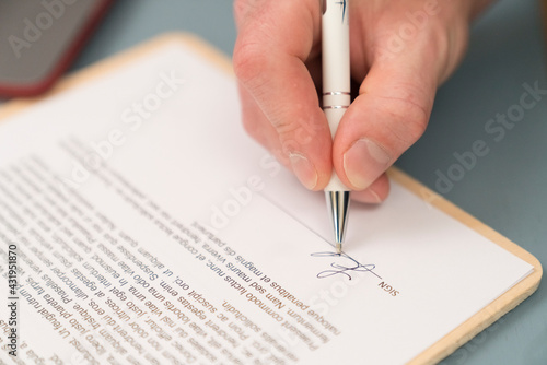 Close-up of businessman giving signature on contract paper at home photo