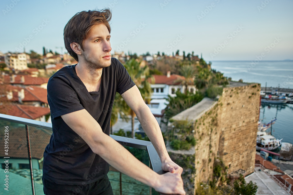 Pensive European man looks at old city in Antalya from vantage point.