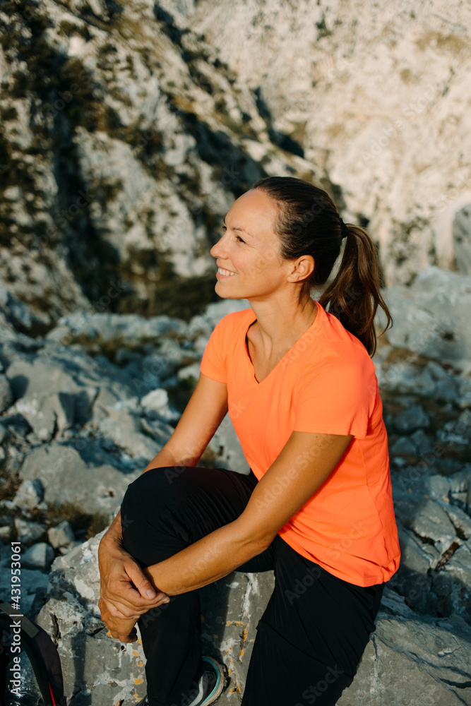 Smiling woman admiring view while sitting on mountain at Cares Trail in Picos De Europe National Park, Asturias, Spain Smiling woman admiring view while sitting on mountain at Cares Trail in Picos De Europe National Park, Asturias, Spain