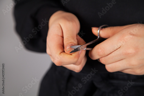 Caucasian woman cuts her nails with scissors.