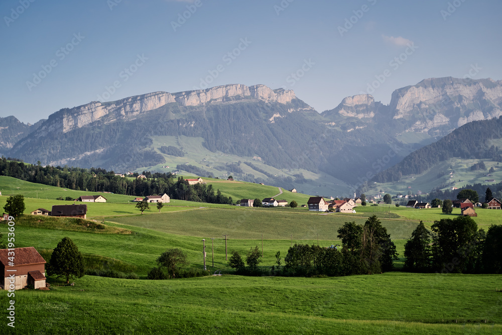 Beautiful summer landscape with houses on green field, Swiss Alps Mountains.
