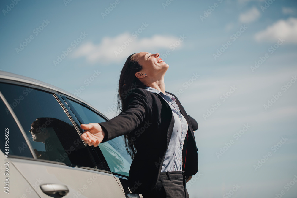 Carefree businesswoman smiling while standing with arms outstretched against sky Carefree businesswoman smiling while standing with arms outstretched against sky
