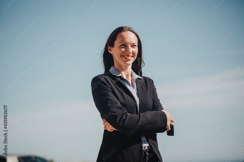 Confident female professional smiling while standing with arms outstretched against sky Confident female professional smiling while standing with arms outstretched against sky