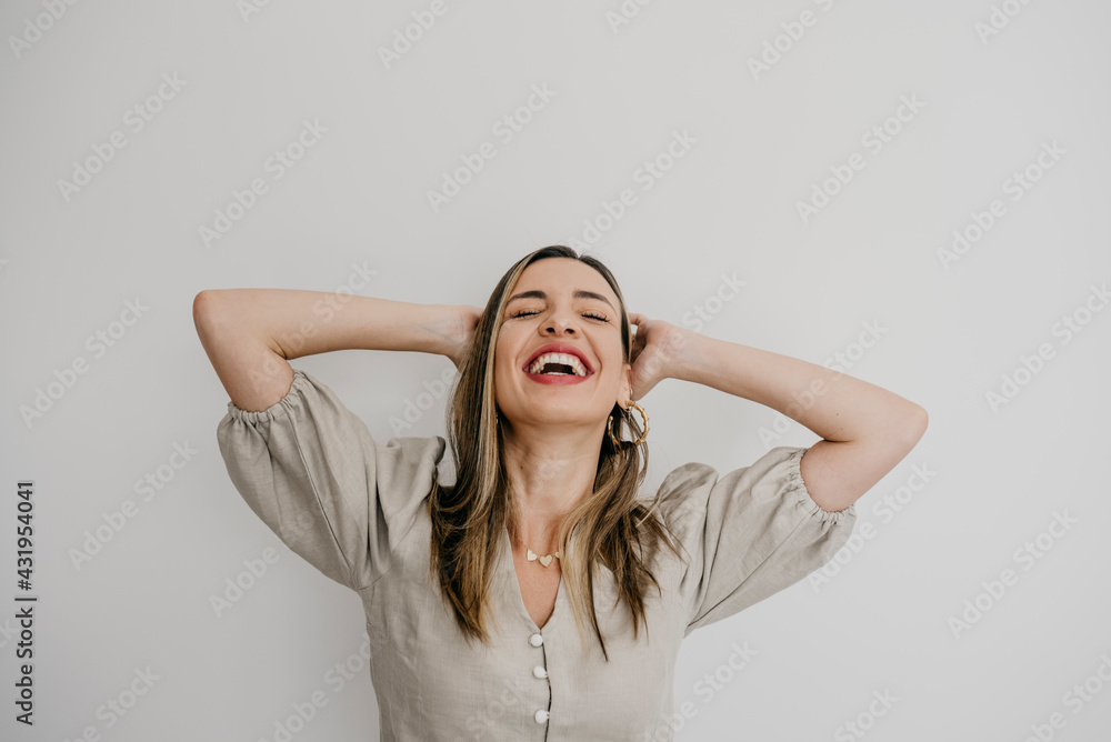 Laughing woman with hands behind head against white background Laughing woman with hands behind head against white background