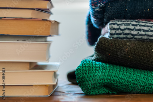 Stacks of books and sweaters on the shelf.