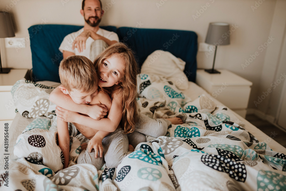 Father watching girl and boy playing at bed Father watching girl and boy playing at bed