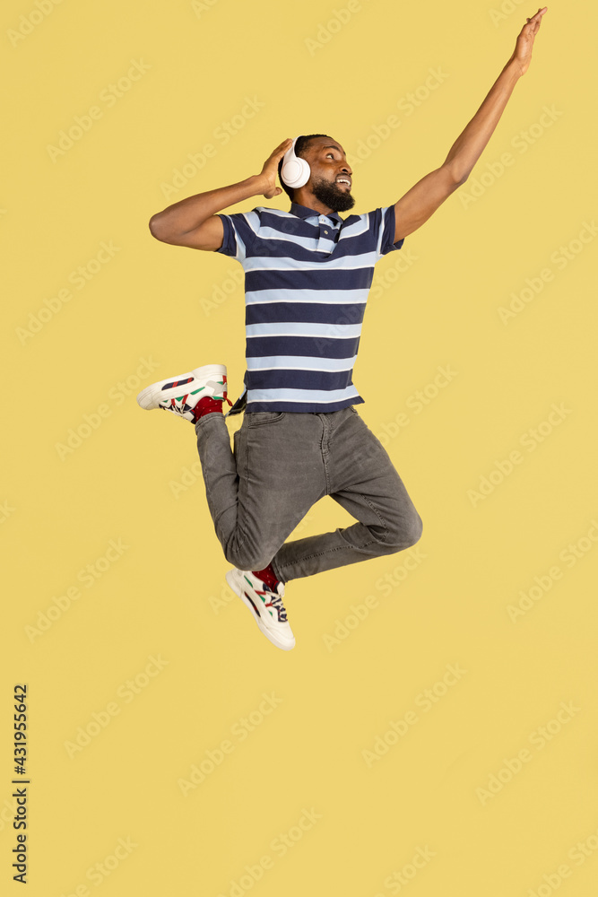 One African young man jumping isolated over yellow studio background with copyspace for ad