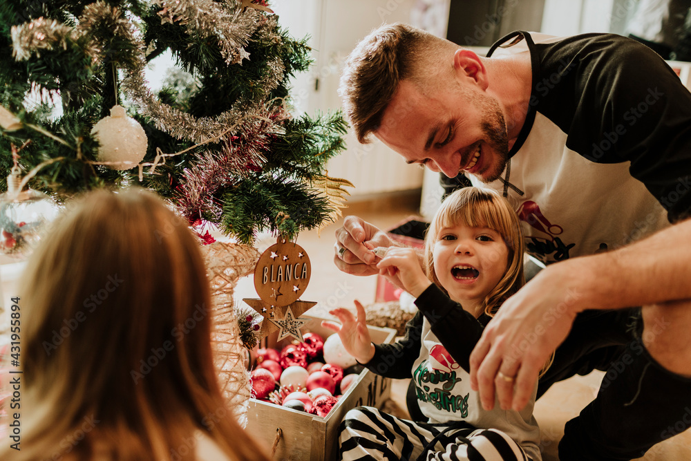 © Gala Mart√≠nez L√≥pez/Westend61 - Happy family decorating christmas tree at home